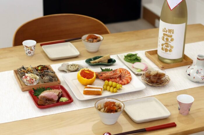 日本らしいおせちと日本酒のボトルが並ぶお正月の食卓